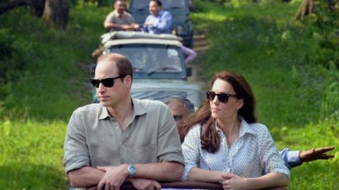 The Duke and Duchess of Cambridge standing up on the back of a jeep