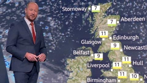 BBC Weather's Darren Bett standing in front of UK's weather map