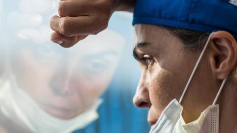 Overworked healthcare worker looking through a window (file image)