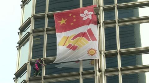 Stunt man Alain Robert ties banner to skyscraper