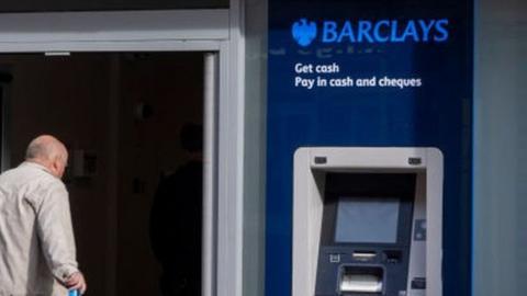 Man walking into a Barclays bank branch