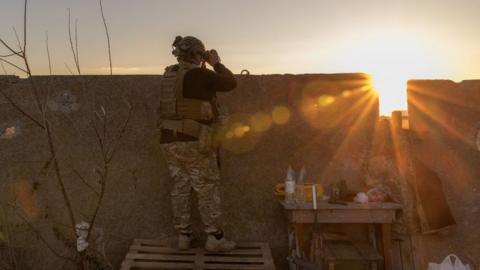 A Ukrainian serviceman of the 123rd Territorial Defense Brigade watches an area of the Dnipro River