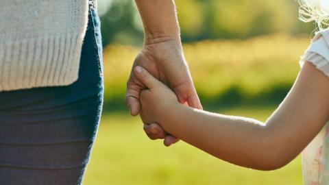 Cropped shot of a little girl holding a woman’s hand