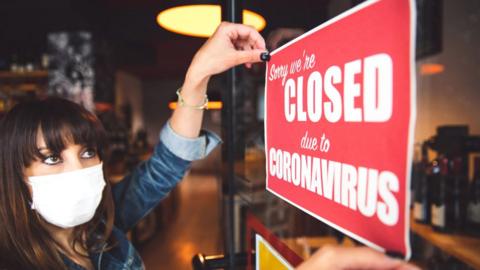 Woman hangs 'Closed for coronavirus' sign