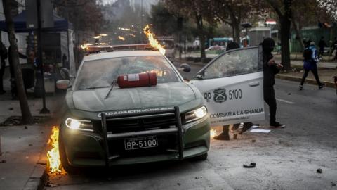 High school students destroy a police car in the centre of the city of Santiago during the demonstration against the "safe classroom" policy promoted by the government of Sebastián Piñera, in Santiago, Chile, on June 24, 2019