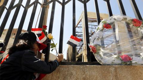 A Yemeni girl puts roses in front of a destroyed funeral hall, a week after Saudi-led airstrikes hit it, during a rally in solidarity and honour of the victims of the 8 October airstrikes, in Sanaa, Yemen, on 15 October 2016