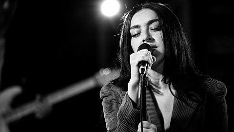 Charli XCX sings into a microphone