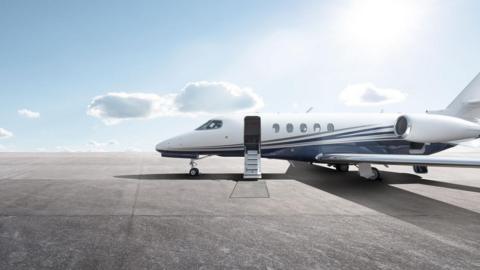 Private jet sat on a runway with the door open and stairs coming out of it