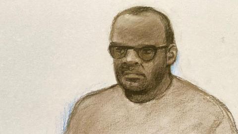 Court sketch of Simon Levy, wearing a beige tracksuit and glasses.