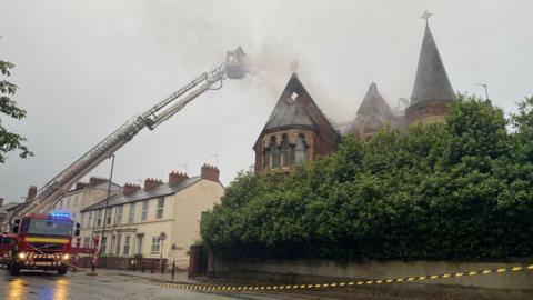Aerial ladder platform and police cordon at smoking building