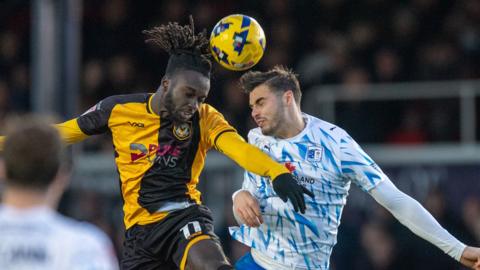 Newport County's Cameron Antwi climbs high for a header against Barrow