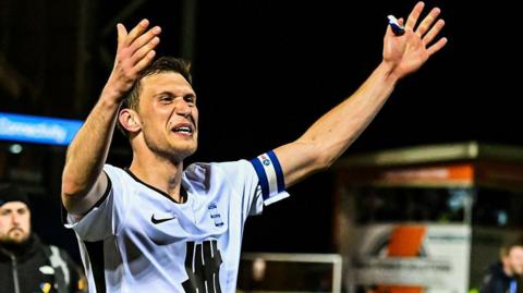 Krystian Bielik holds his arms aloft in celebration