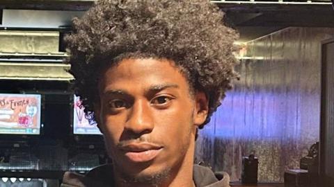 Rinneau Perrineau is looking at the camera wearing a neutral expression