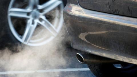 The picture shows a plume of white fumes coming out of a car's exhaust pipe