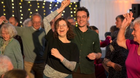 Daoine a' dannsa aig cèilidh.