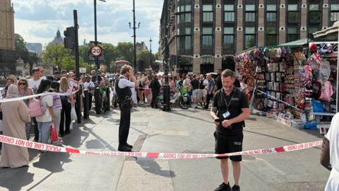 Crowds stand behind a police cordon close to Westminster Bridge in central London.