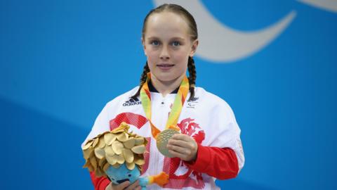 Ellie Robinson holding her gold medal 