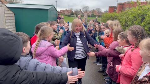 A woman receiving a guard of honour from school children