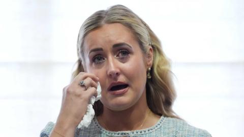 Katie Amess in tears holding up a tissue to her right eye.