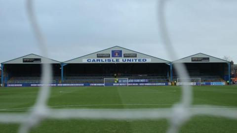 A view of the Warwick Road terrace at Carlisle's Brunton Park ground from through the netting at the other end