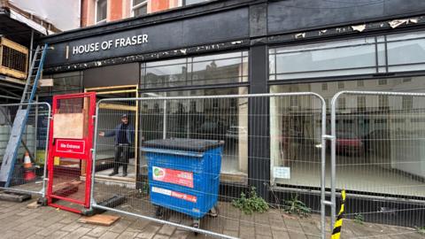 Co-founder of The Long Table, Tom Herbert, outside the old House of Fraser building sandwiched between the door and the scaffolding.