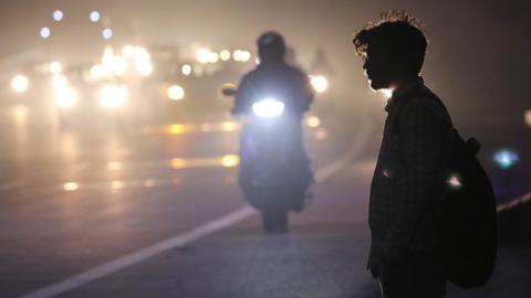 A person stands on roadside in heavy smog near New Delhi, India, 09 November 2023