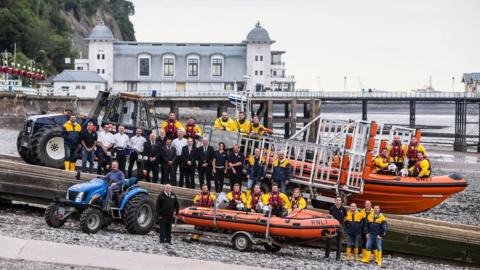 A group picture of RNLI Penarth's crew in front of Penarth Pier