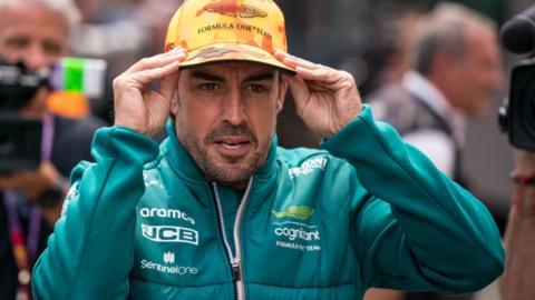Fernando Alonso adjusts his cap in the Barcelona paddock