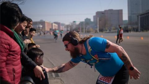 A foreign competitor talks to a child on the roadside of Pyongyang at the marathon on April 7