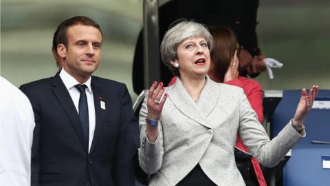 Theresa May standing next to French President Emmanuel Macron