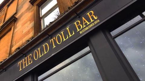The entrance to the Old Toll Bar pub, with the name written in in gold on a black background