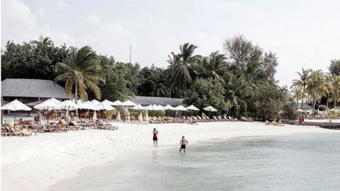 A couple taking photos on the beach in the afternoon during their honeymoon in The Maldives