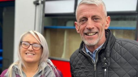 Abbie and Mark Butcher stood next to bus