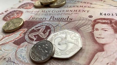 Manx money - coins laid out on top of £20 notes.