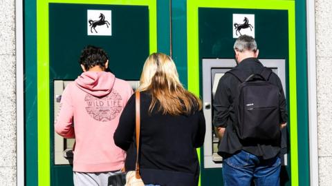 Customers queuing at an ATM