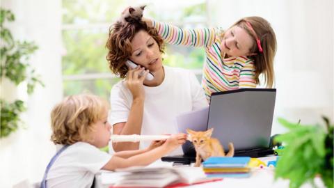 Woman working at home, with her children