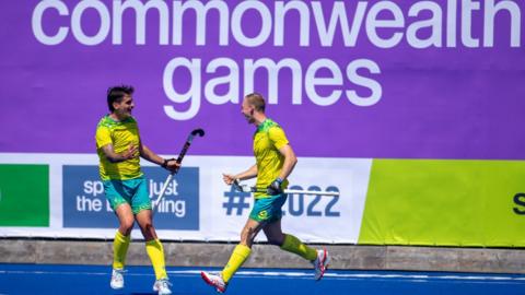 Hockey players celebrate in front of Commonwealth Games signage