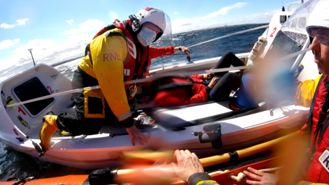 A lifeboat volunteer boarded the rowing boar to assess the sick man