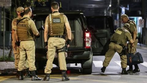 Police collect money left behind by assailants in the aftermath of a bank robbery in Criciuma, Brazil, 01 December 2020.