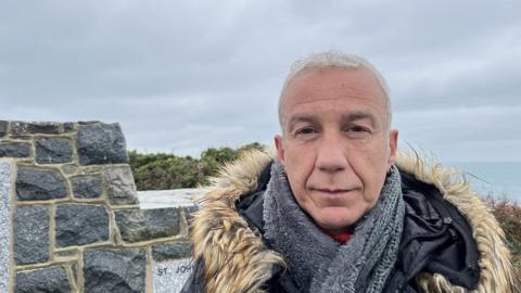 Evangelos Giagkoudakis standing at the Prosperity memorial in Guernsey