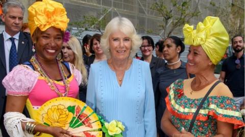 Camilla poses with two ladies in traditional Cuban clothing