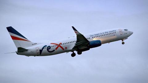 Rex Airlines Boeing 737 plane flying through the air with clouds surrounding it