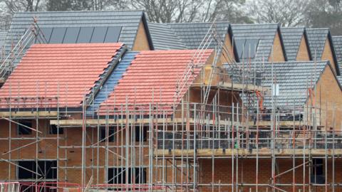 Scaffolding is set up around several houses under construction.