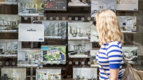 Woman looking in estate agent's window