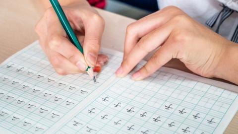 Hand of student writing Chinese characters