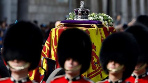 The coffin of Queen Elizabeth II, draped in the Royal Standard with the Imperial State Crown placed on top, is carried along Whitehall on a horse-drawn gun carriage of the King's Troop Royal Horse Artillery, during the ceremonial procession from Buckingham Palace to Westminster Hall, London, where it will lie in state ahead of her funeral on Monday. Picture date: Wednesday September 14, 2022.