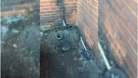 a wall with a burnt out power cable next to a building 