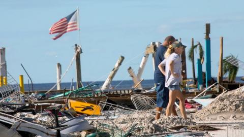 People walk past destruction at Fort Myers Beach, Florida, on Friday 30 September