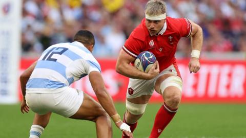 Wales number eight Aaron Wainwright is challenged by an Argentina player as he runs with ball 