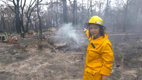 91ȱ's Sydney Correspondent Shaimaa Khalil stands amid burnt trees and flattened land in Balmoral, Australia.